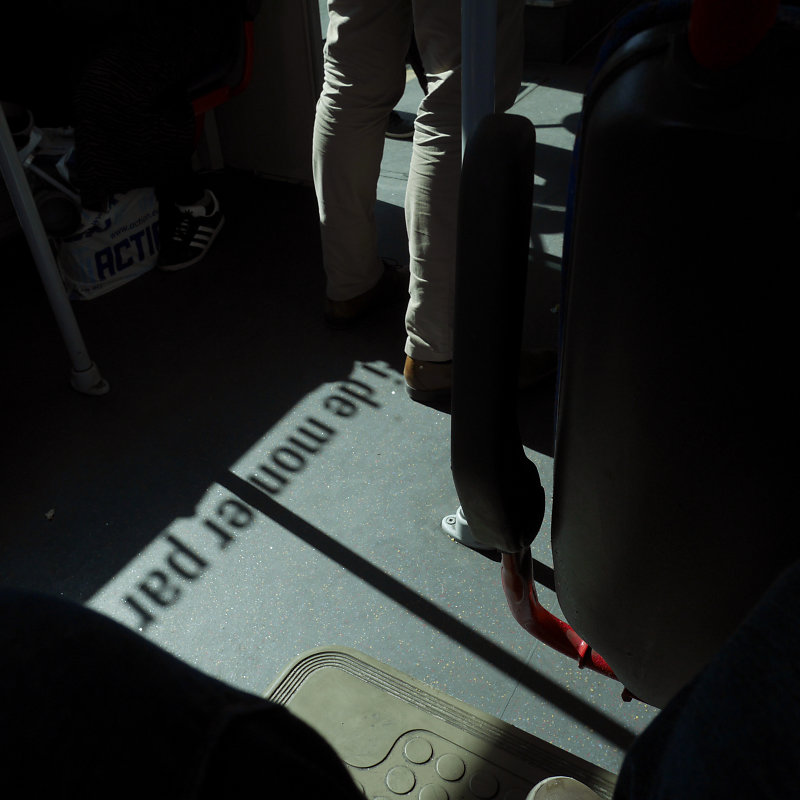 merci de monter par l'avant est écrit en ombre et en lumiere au pied de voyageur d'un bus
