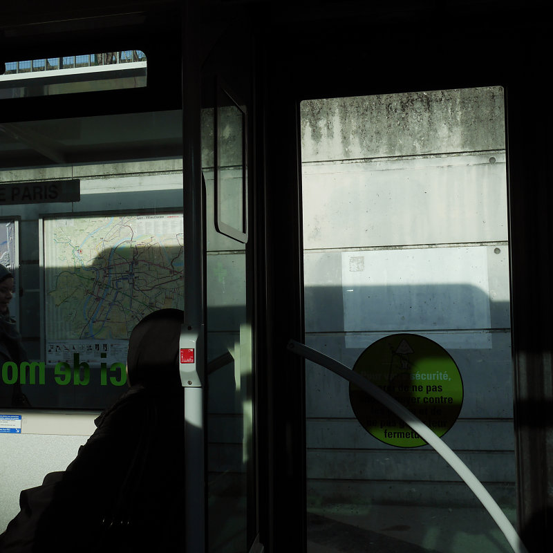 2 formes se répondent une femme assise voilée et la barre de maintien dans un bus