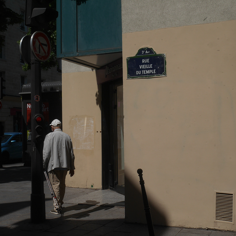 Homme de dos avec une casquette blanche, marchant rue Vieille du Temple à Paris